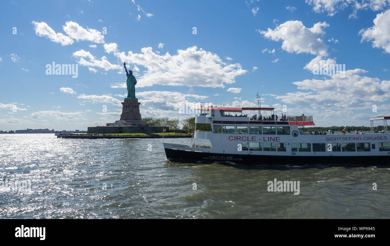 New York, Stati Uniti d'America. White cruiser barca davanti alla statua della Libertà. L'estate. Attrazione turistica. Teste in barca al molo del Liberty Island Foto Stock