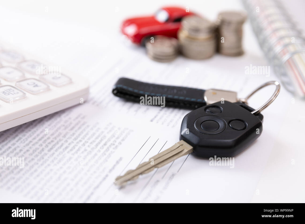 Acquistare auto concetto. Le chiavi dell'auto, calcolatrice, giocattolo auto, monete e contratto di acquisto Foto Stock