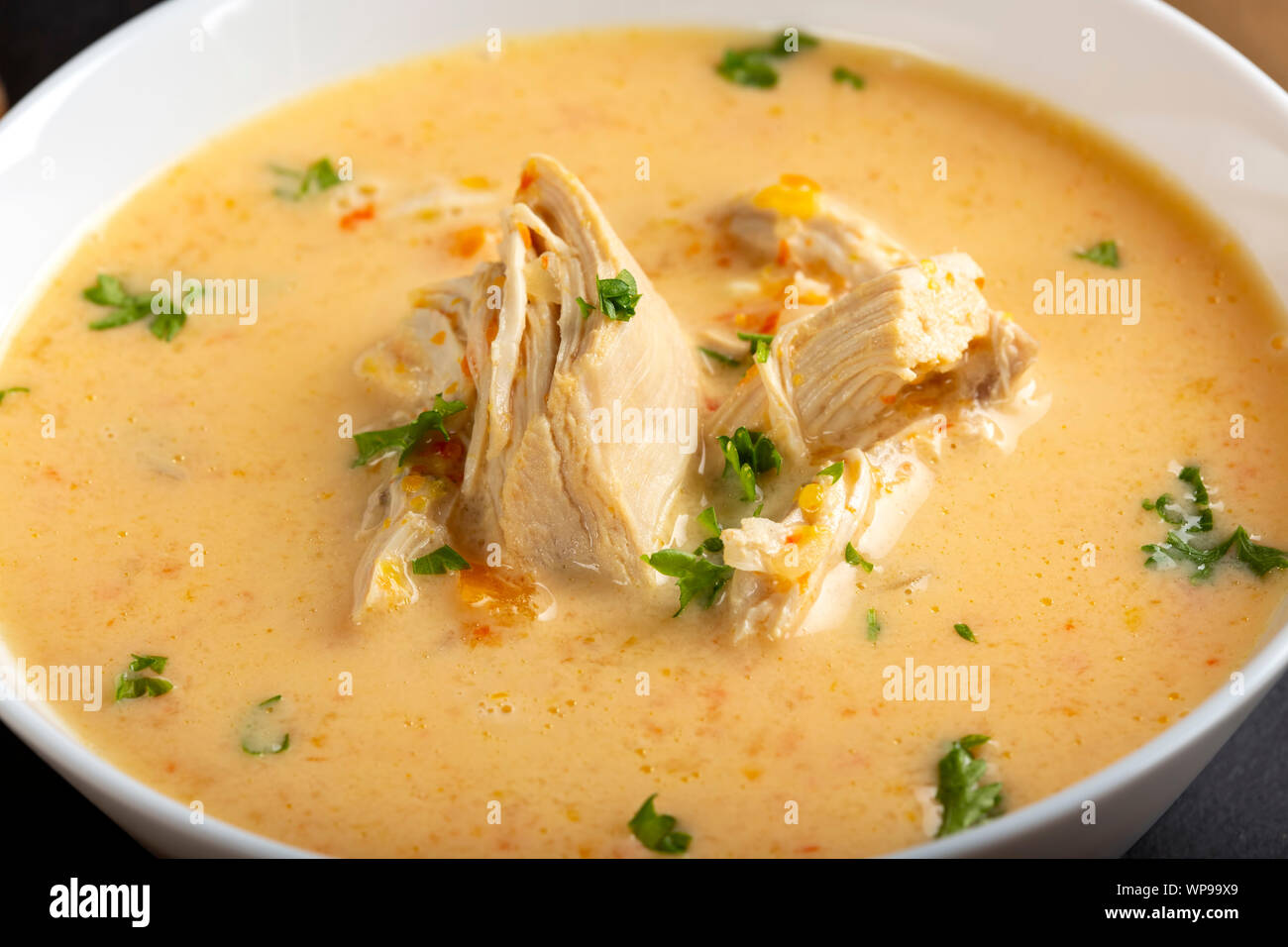 Ciorba radauteana - rumeno tradizionale zuppa di pollo con panna e aglio in una ciotola bianco Foto Stock