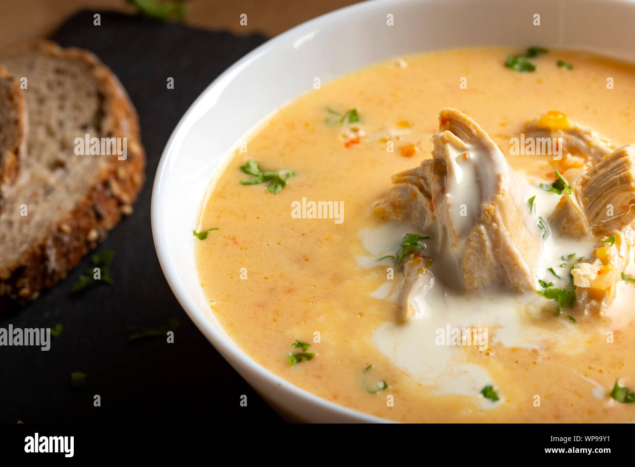 Ciorba radauteana - rumeno tradizionale zuppa di pollo con panna e aglio in una ciotola bianco Foto Stock