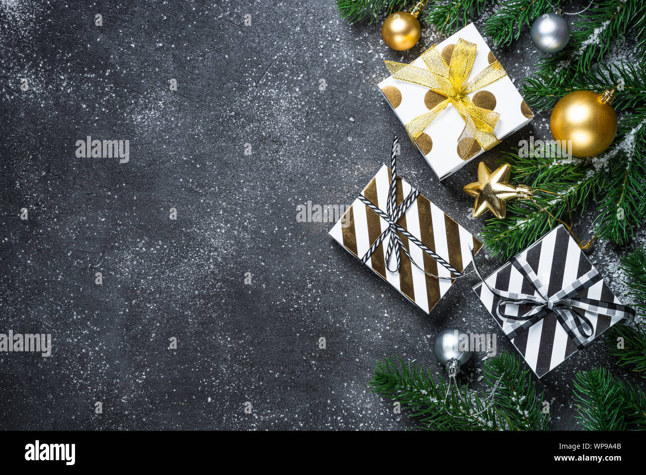 Sfondo di natale - Oro e argento decorazioni e presente sulla scatola di pietra nera dello sfondo. Foto Stock