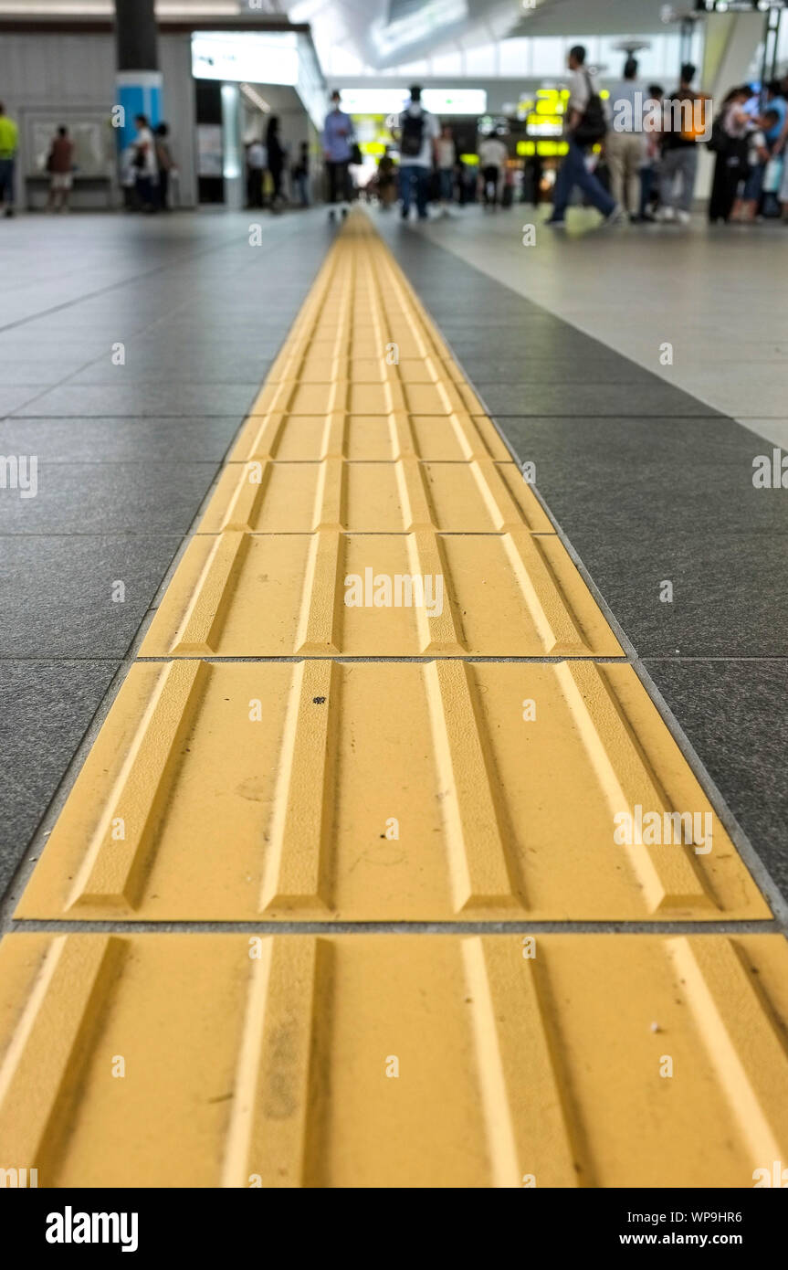 Le linee gialle chiamato "tattile della superficie del terreno indicatori" (TGSI) o blocchi tenji. In Osaka stazione ferroviaria, di Osaka in Giappone. Foto Stock