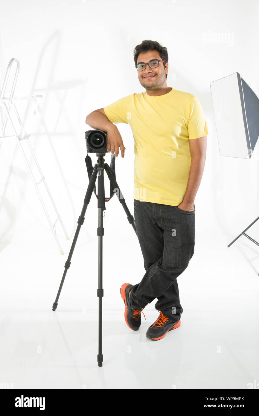 Fotografo appoggiato su di una fotocamera digitale in studio Foto Stock