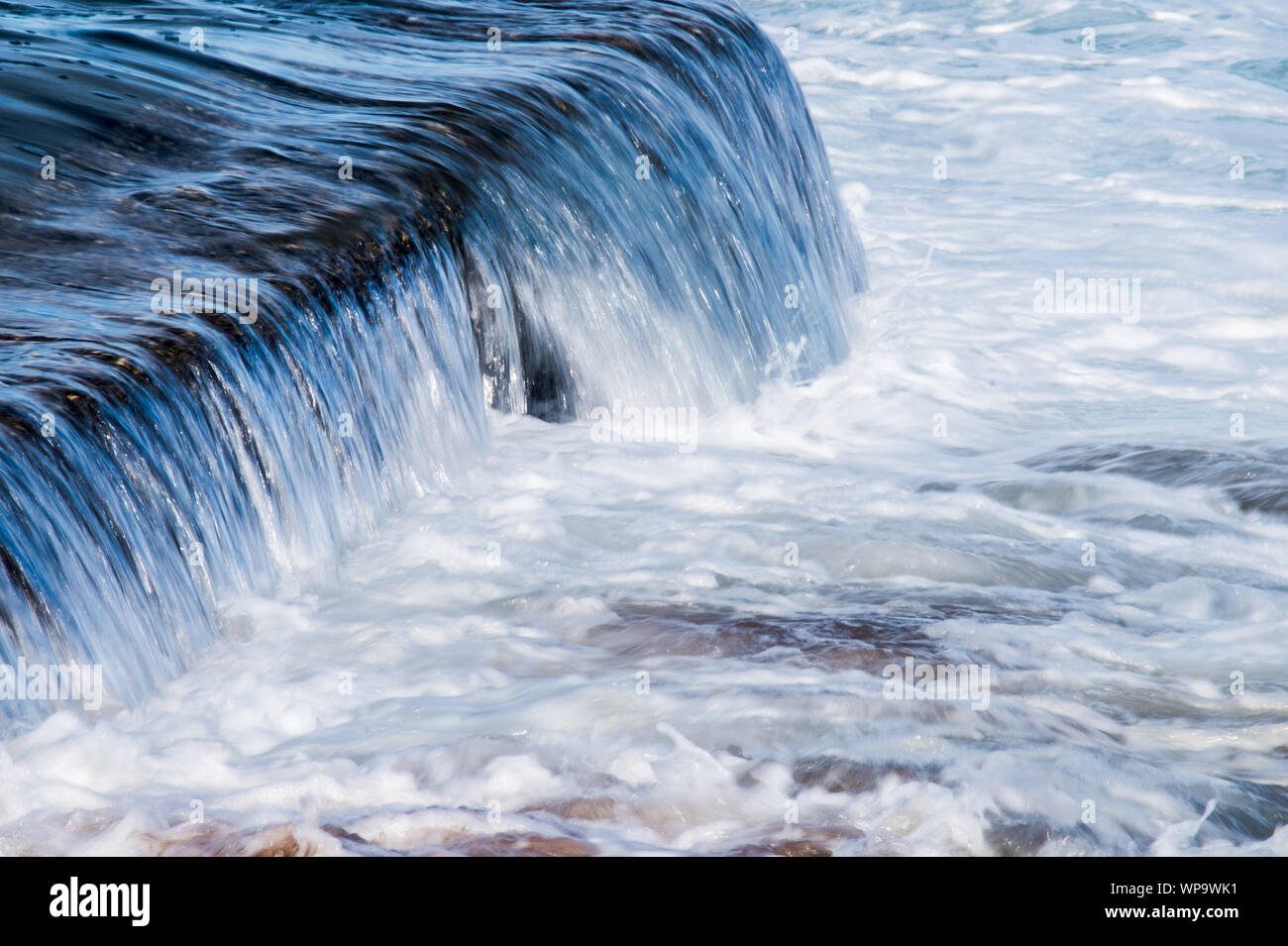 Pomeriggio Un forte, marea con onde che si infrangono su un pool di marea parete e creando una potente overflow surf schiumoso come risacca schiantarsi Foto Stock