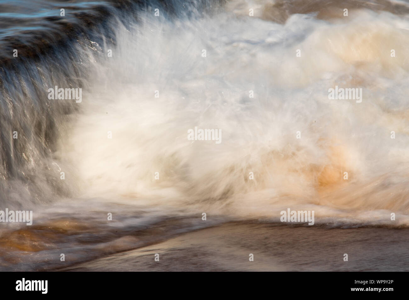 Pomeriggio Un forte, marea. Le onde sono di schiantarsi su una marea di parete della piscina e creando un potente flusso di ritorno. Surf schiumoso e potenti flussi di crash Foto Stock