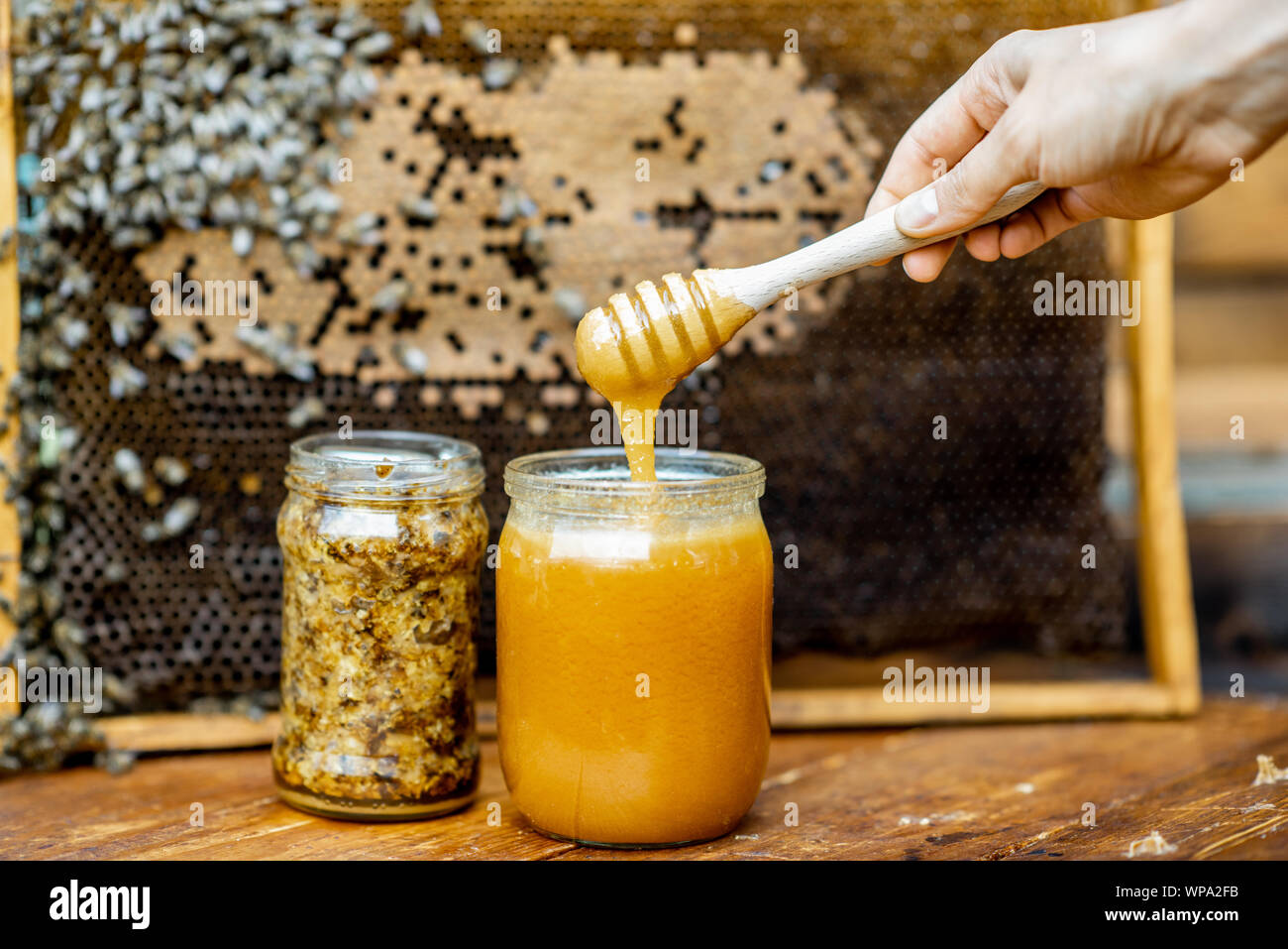 Vaso con miele fresco sull'alveare con il nido d'ape sullo sfondo Foto Stock