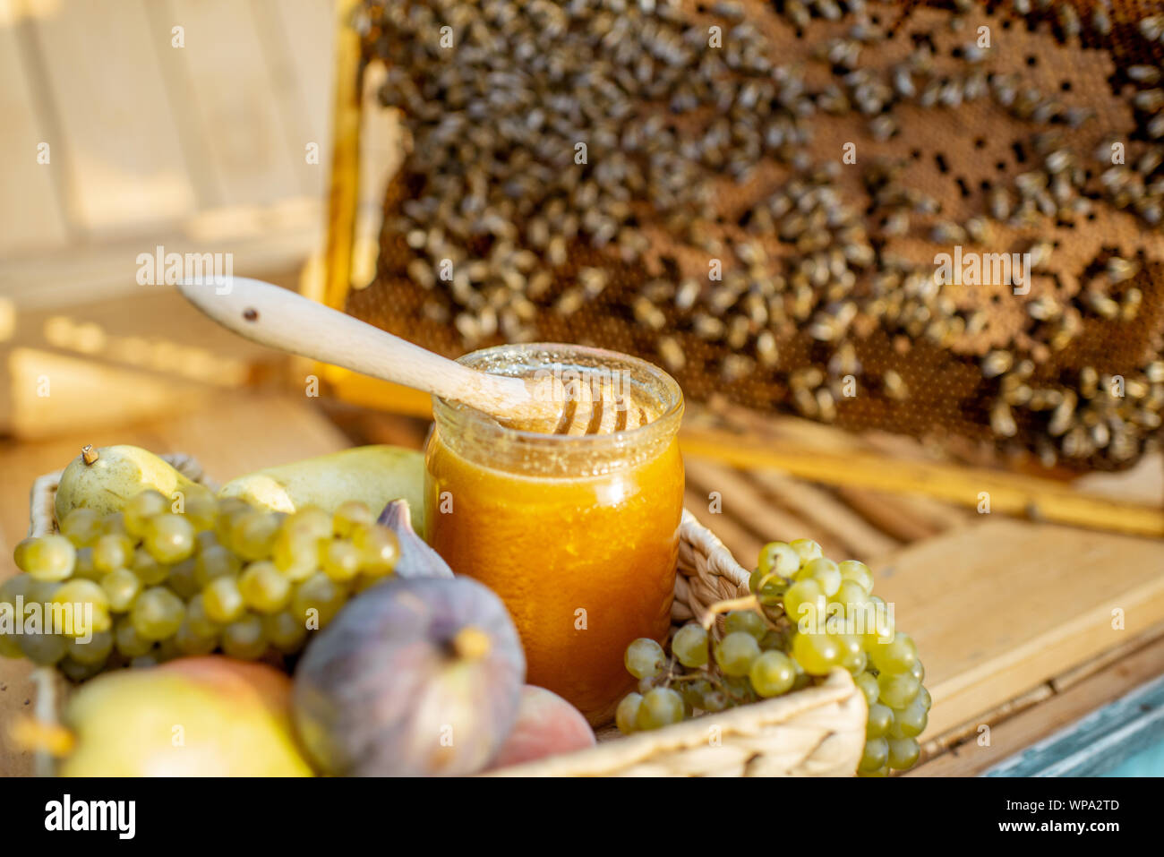 Composizione di frutti dolci e jar con del miele per alveare con il nido d'ape sullo sfondo Foto Stock