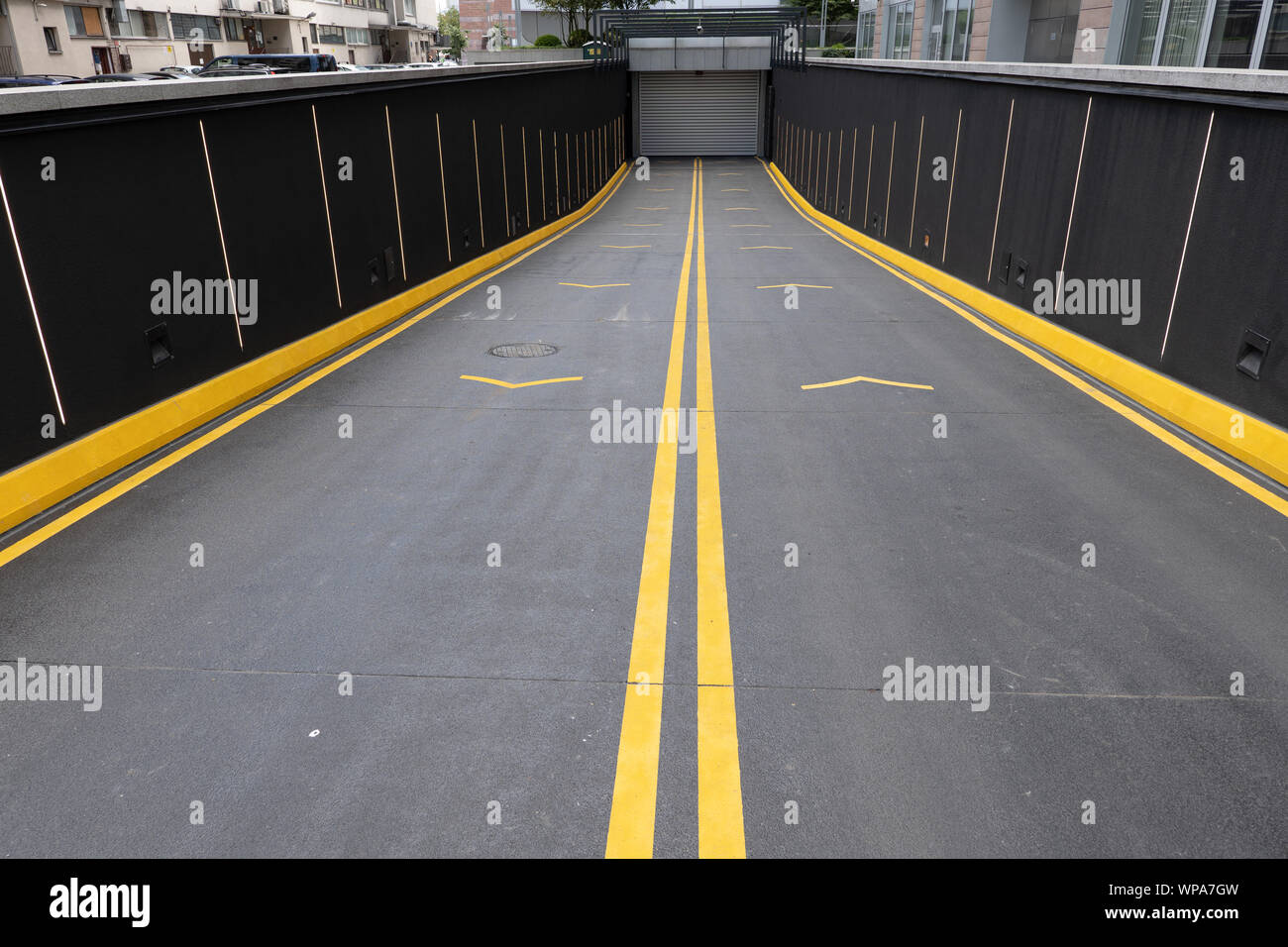 Ingresso dalla strada di un garage per il parcheggio sotterraneo in città, laballed vivaci con vernice gialla. Foto Stock