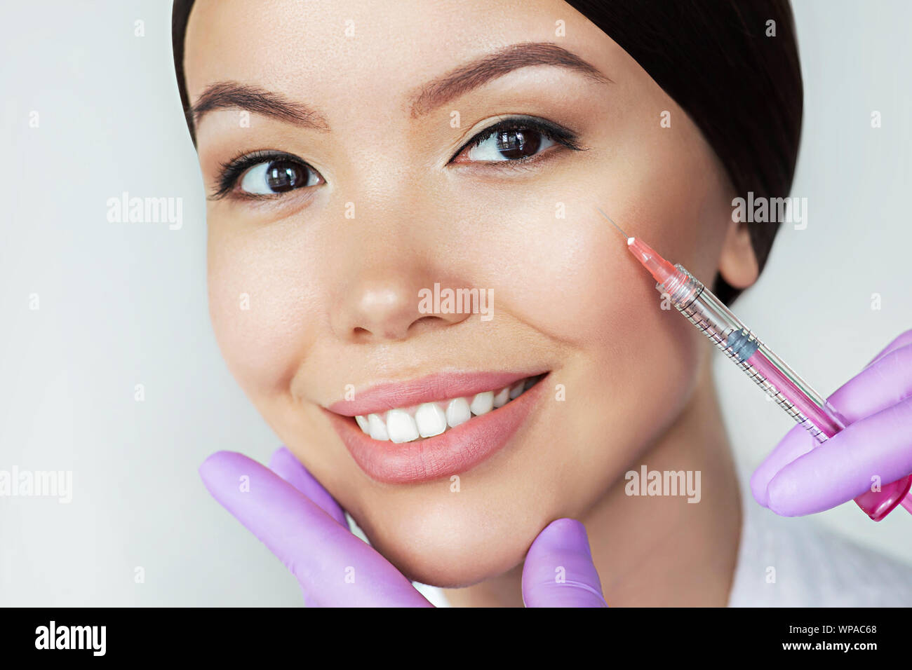 Bella donna asiatica ottiene iniezioni di bellezza. Close-up iniezione di anti-invecchiamento e rughe perfetto volto femminile Foto Stock