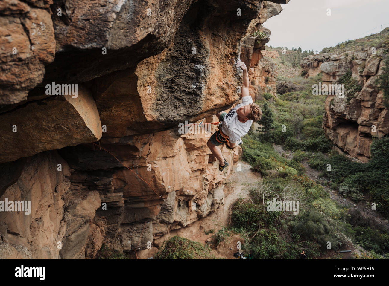 Un giovane scalatore portano la scalata su un percorso a sbalzo Foto Stock