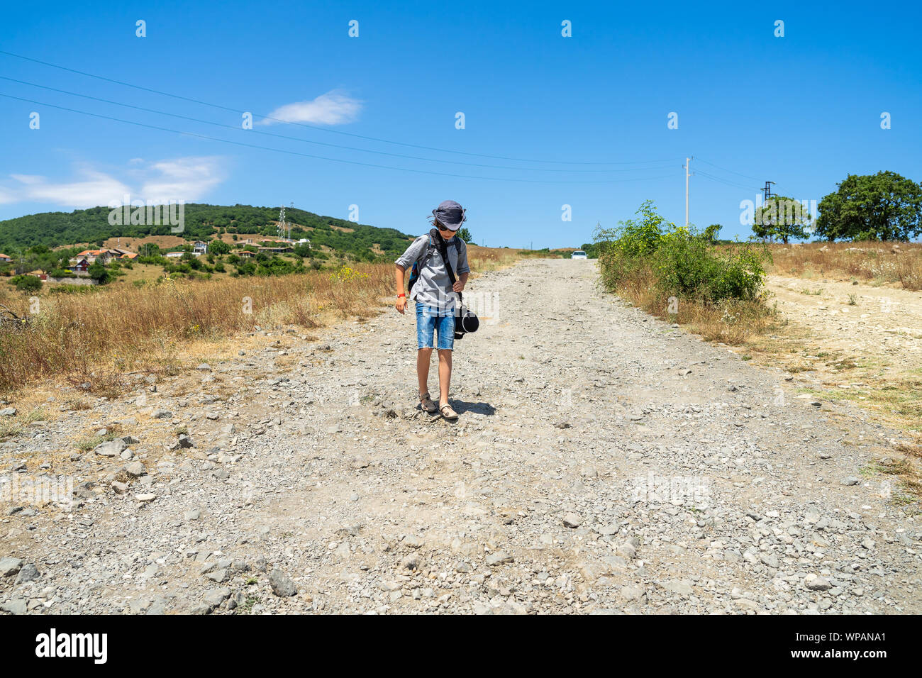 Un ragazzo pieno di sacchetti è su una strada sterrata. Foto Stock
