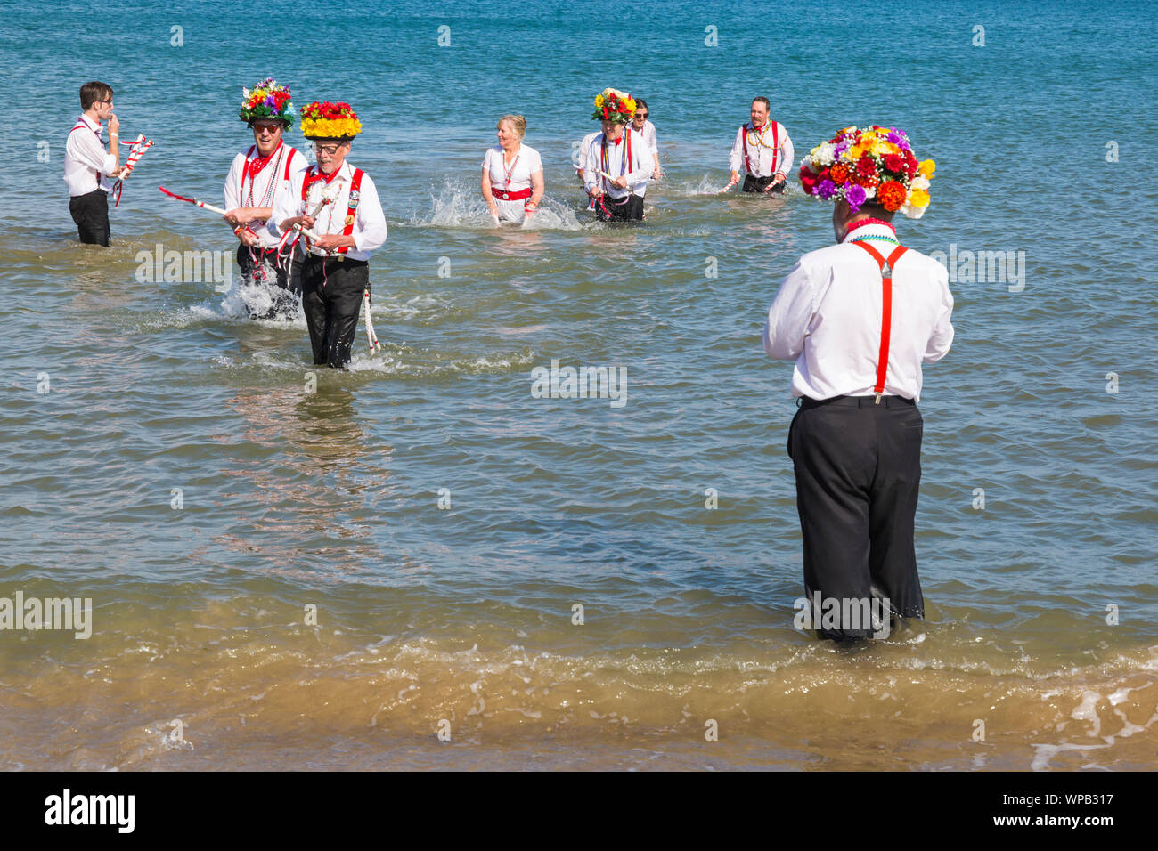 Swanage, DORSET REGNO UNITO. 8 settembre 2019. La folla affollano la città balneare di Swanage per godere della danza, con oltre 50 squadre di danza tra cui morris dancing a Swanage Folk Festival. Ballerini di Morris dance in mare al termine della due giorni del festival in un giorno caldo e soleggiato. Basingclog Morris ballerini danzare in mare. Credito: Carolyn Jenkins/Alamy Live News Foto Stock