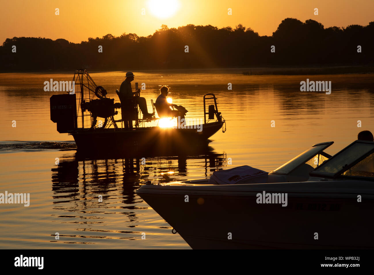 I pescatori escono in un piccolo powerboat e un'airboat all alba di un giorno di avventura in un lago della Florida. Foto Stock