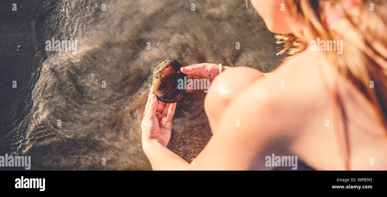 Ragazza che gioca con il guscio in acqua poco profonda sulla spiaggia Foto Stock Ragazza che gioca con il guscio in acqua poco profonda sulla spiaggia Foto Stock