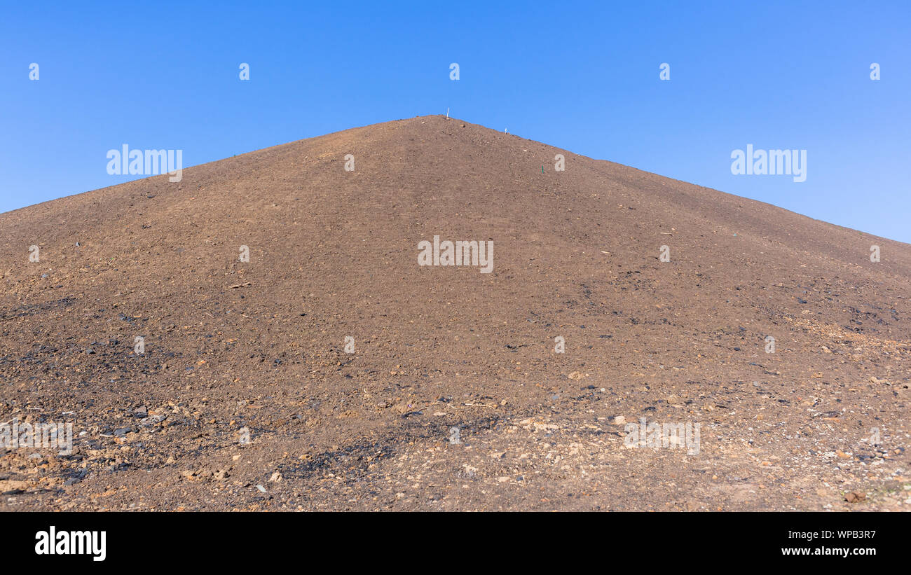 Alta sabbia marrone texture argine della costruzione della piattaforma di paesaggio di scavo Lavori di sterro verso l'alto con il blu del cielo. Foto Stock