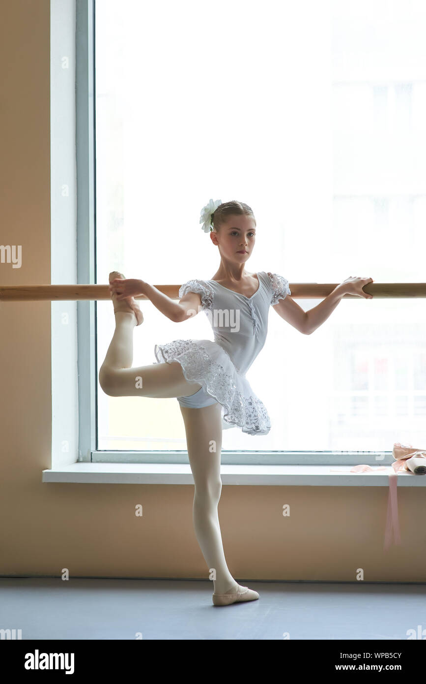 Ballerina in abito bianco che posa a barre. Foto Stock