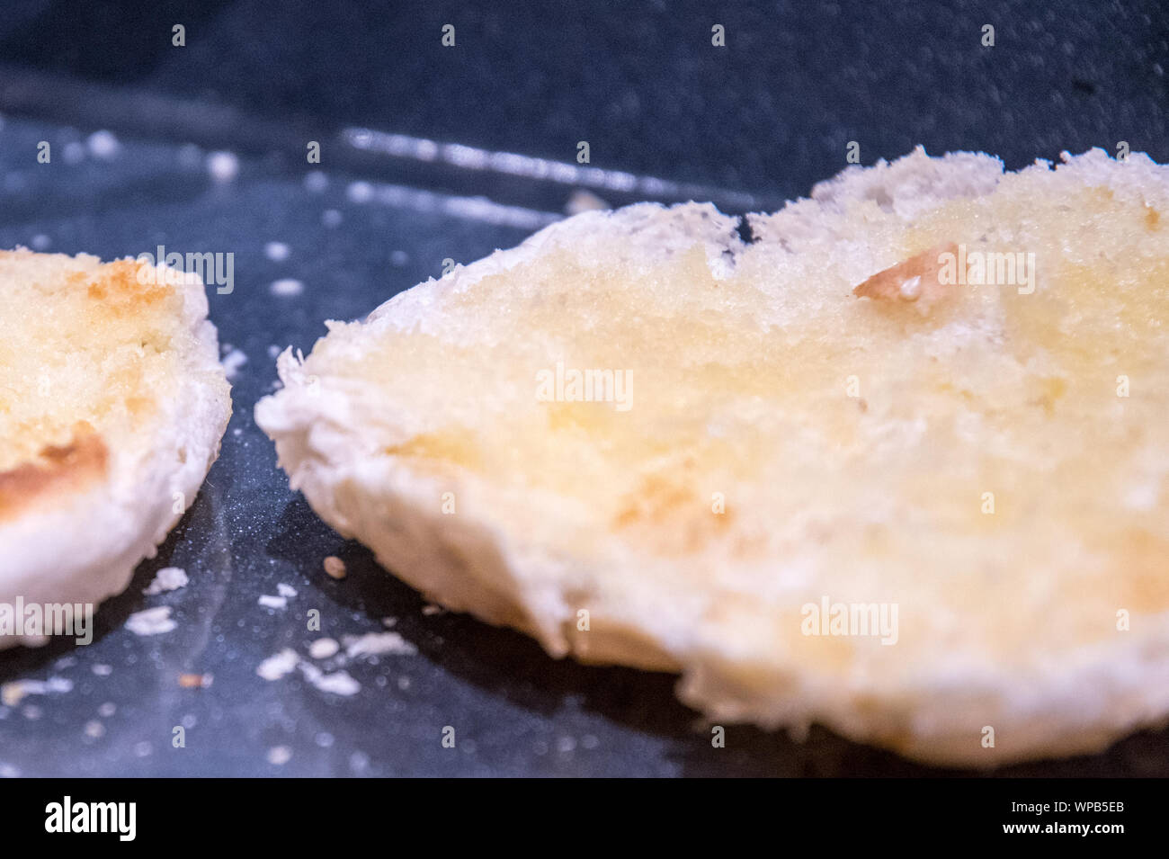 Tagliato e aperto rotoli imburrati e su un vassoio tostato con briciole nel vassoio. La strato imburrato è una dorata dopo la cottura in forno. Foto Stock