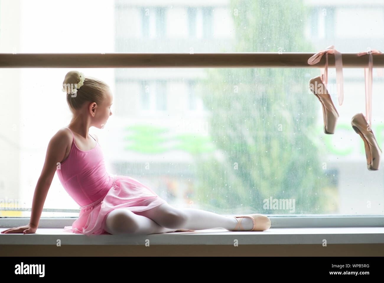 Ballerina giovane che guarda sulla pioggia fuori dalla finestra. Foto Stock