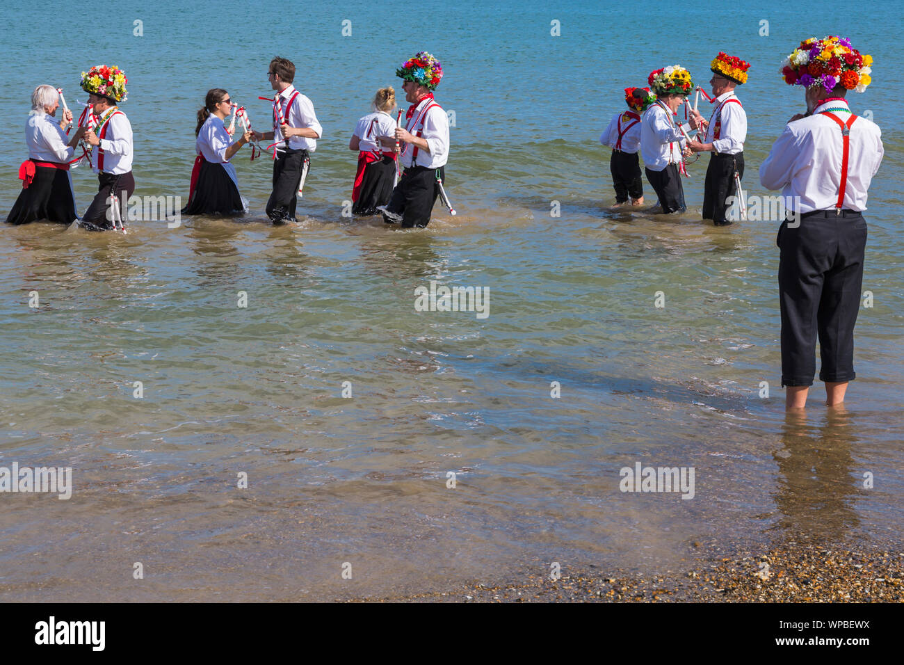 Swanage, DORSET REGNO UNITO. 8 settembre 2019. La folla affollano la città balneare di Swanage per godere della danza, con oltre 50 squadre di danza tra cui morris dancing a Swanage Folk Festival. Ballerini di Morris dance in mare al termine della due giorni del festival in un giorno caldo e soleggiato. Basingclog Morris ballerini danzare in mare. Credito: Carolyn Jenkins/Alamy Live News Foto Stock