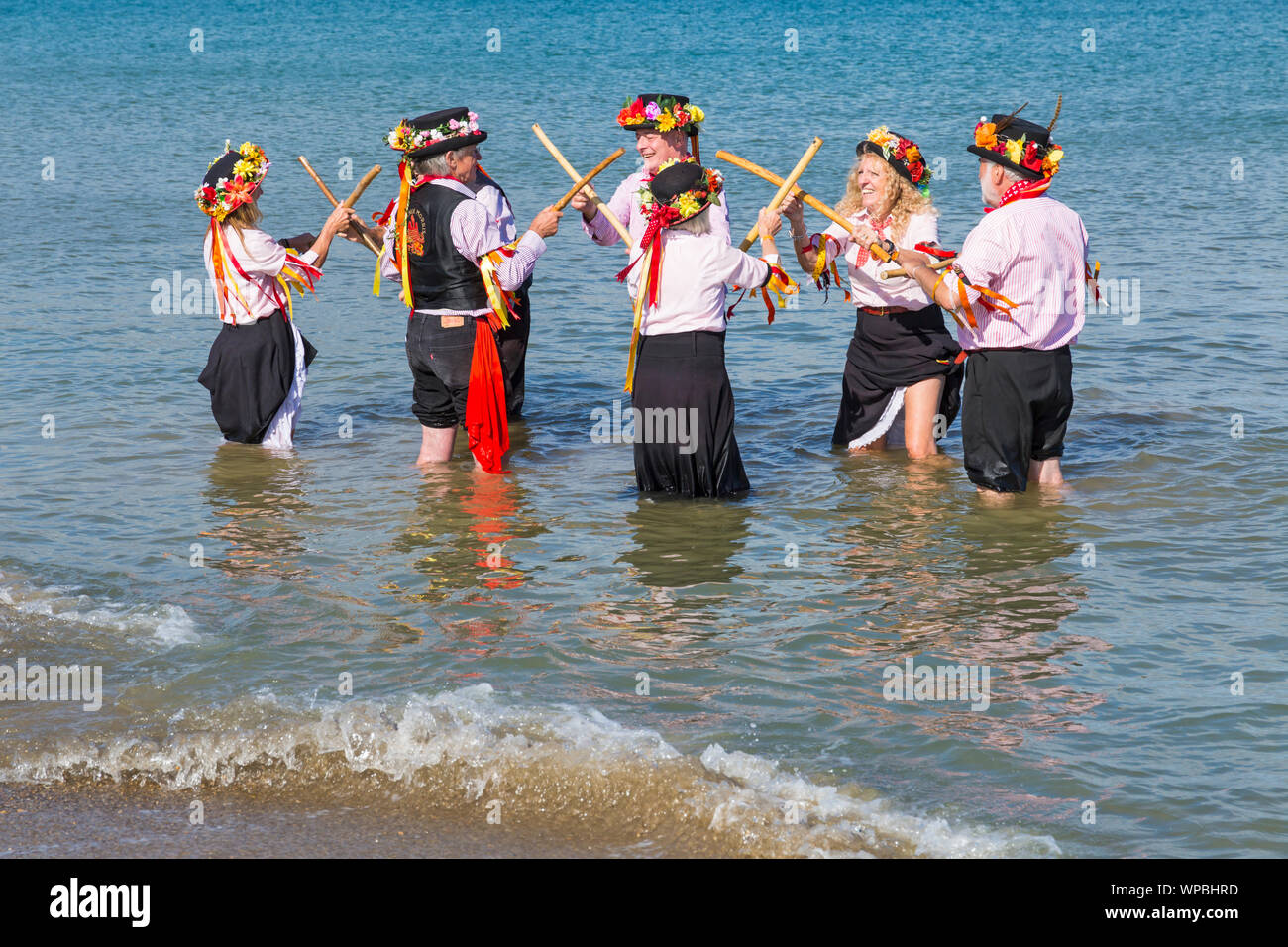 Swanage, DORSET REGNO UNITO. 8 settembre 2019. La folla affollano la città balneare di Swanage per godere della danza, con oltre 50 squadre di danza tra cui morris dancing a Swanage Folk Festival. Ballerini di Morris dance in mare al termine della due giorni del festival in un giorno caldo e soleggiato. Morris ballerini, membri di Phoenix Morris dancing in mare. Credito: Carolyn Jenkins/Alamy Live News Foto Stock