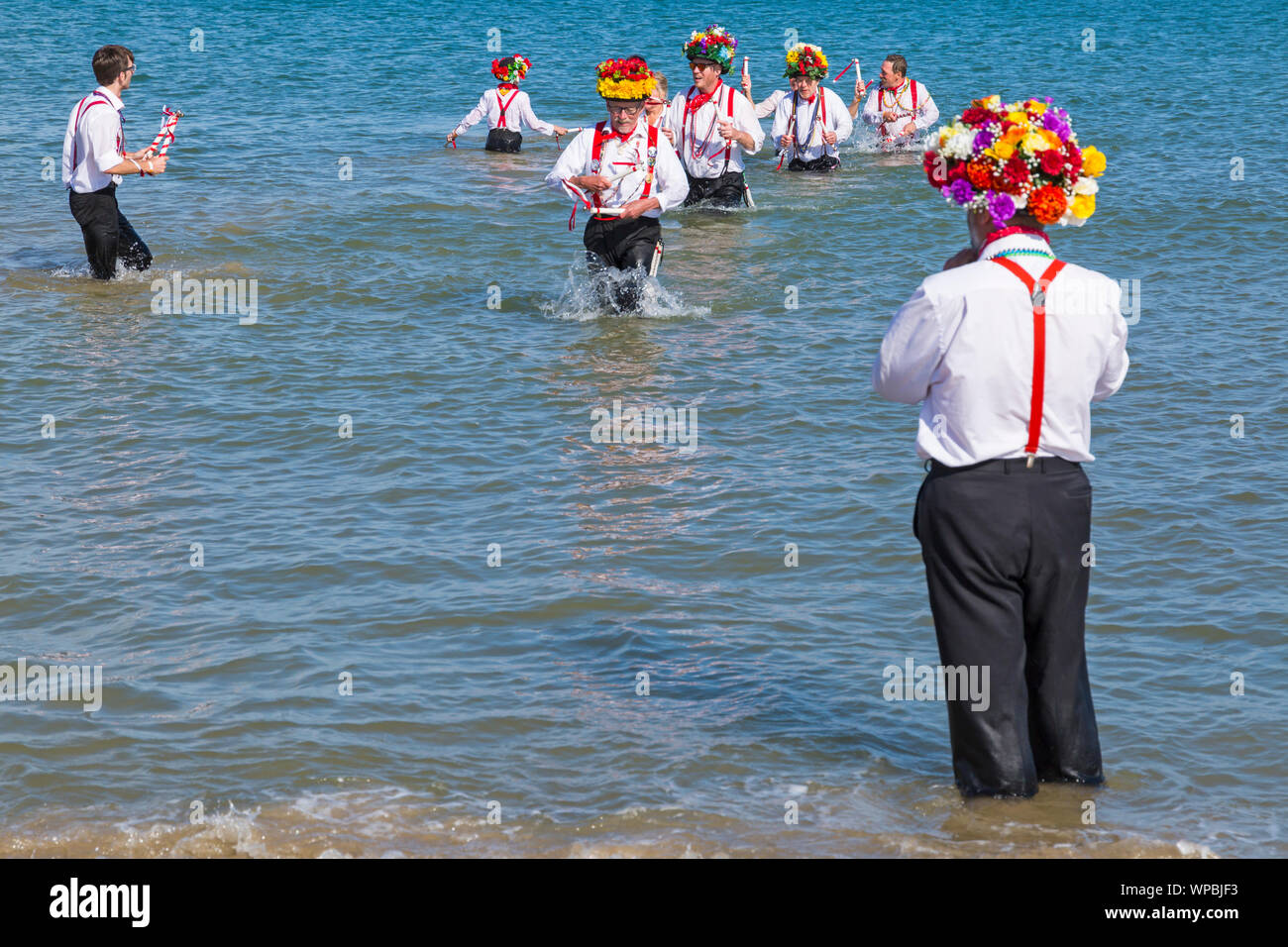 Swanage, DORSET REGNO UNITO. 8 settembre 2019. La folla affollano la città balneare di Swanage per godere della danza, con oltre 50 squadre di danza tra cui morris dancing a Swanage Folk Festival. Ballerini di Morris dance in mare al termine della due giorni del festival in un giorno caldo e soleggiato. Basingclog Morris ballerini danzare in mare. Credito: Carolyn Jenkins/Alamy Live News Foto Stock