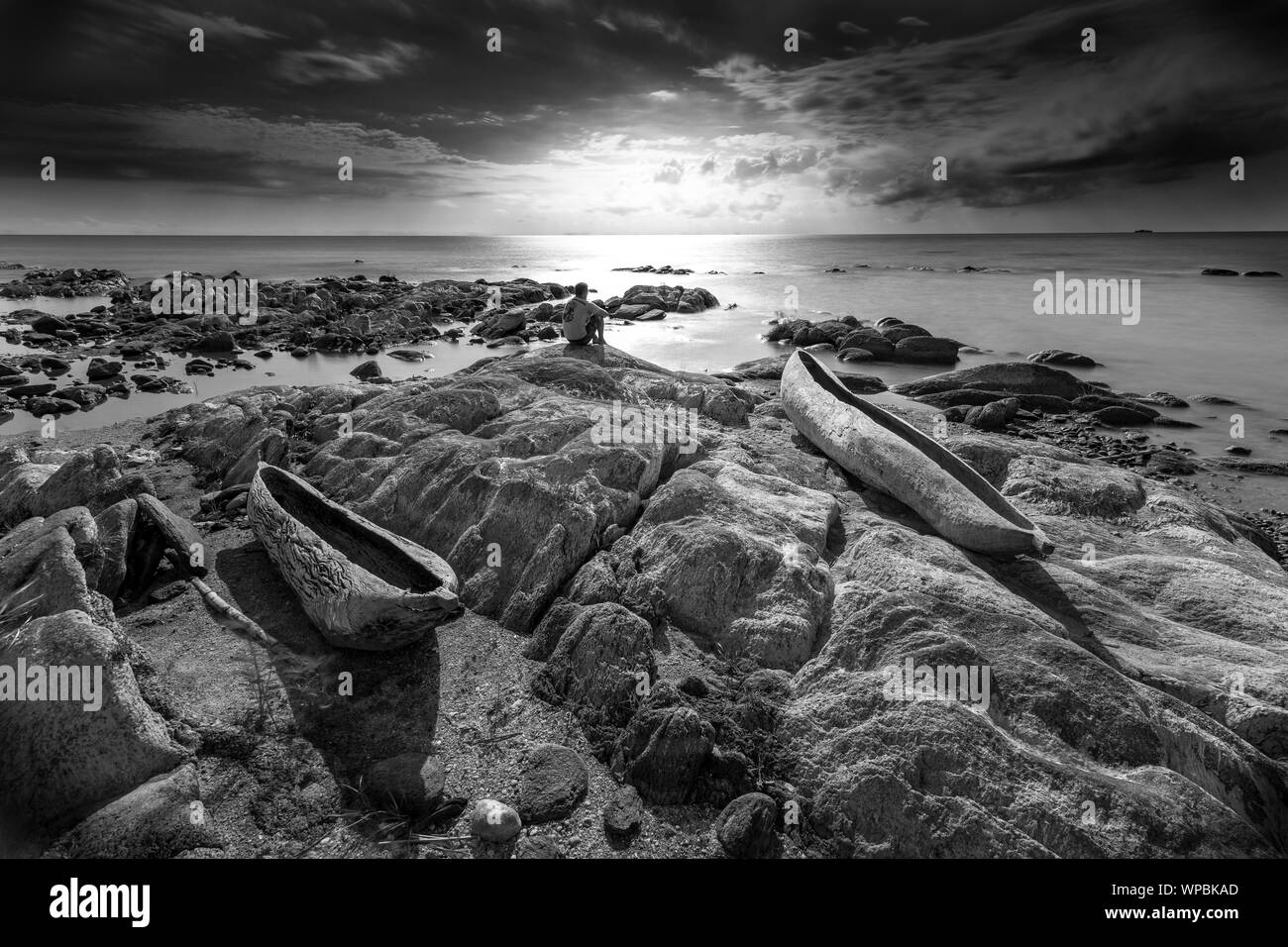 Sunrise vista lago Malawi, onde regolare scorrimento sulla spiaggia, due di legno albero di una barca in primo piano, in Africa, in bianco e nero Foto Stock
