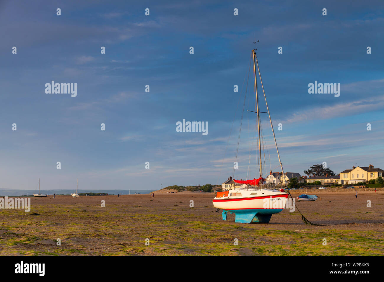 Il sole splende su uno yacht a instow Beach, North Devon con persone a distanza per godersi la spiaggia Foto Stock