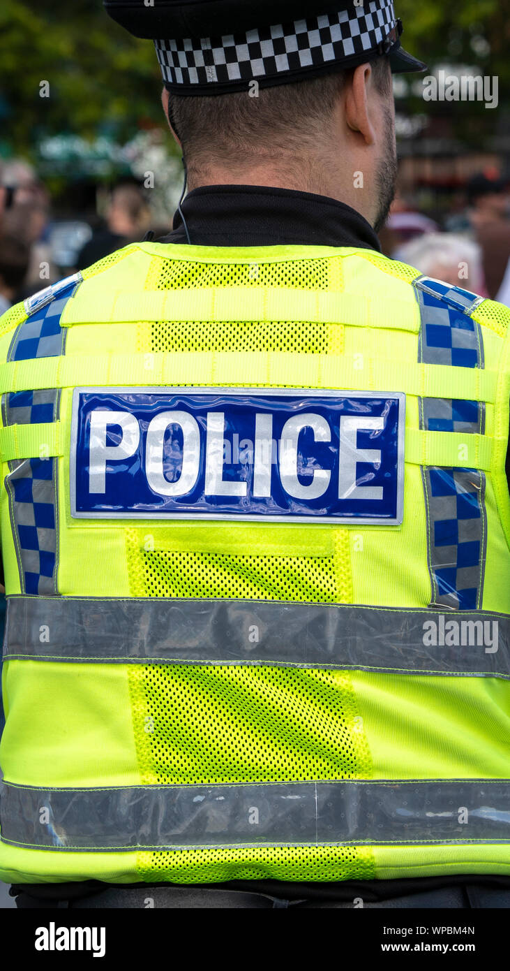 Ufficio di polizia indossando divisa da lavoro ad alta visibilità visto da dietro Foto Stock