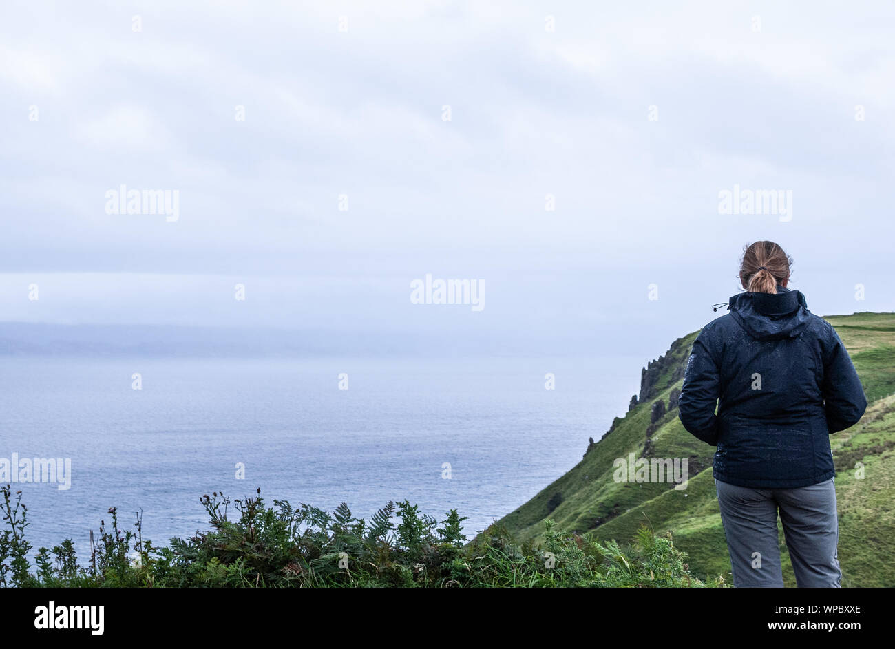 Un felice giovane donna bionda guardando le scogliere che end al mare Foto Stock