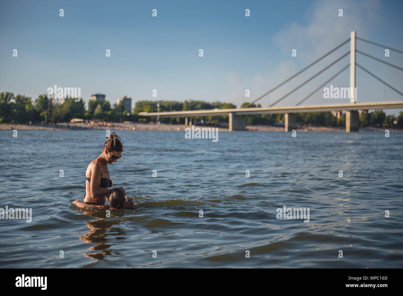 Madre figlia di apprendimento di nuotare nel fiume dal ponte Foto Stock Madre figlia di apprendimento di nuotare nel fiume dal ponte Foto Stock