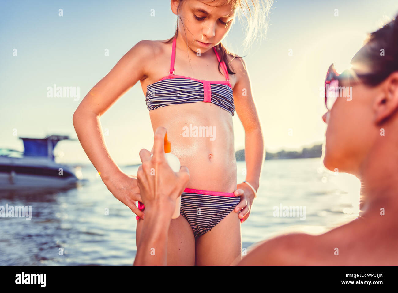 Madre di applicare la protezione solare Crema a sua figlia sulla spiaggia Foto Stock Madre di applicare la protezione solare Crema a sua figlia sulla spiaggia Foto Stock