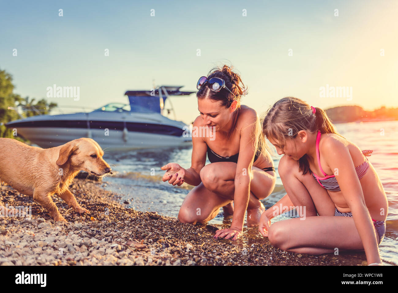 Madre e figlia e small yellow dog godendo sulla spiaggia Foto Stock Madre e figlia e small yellow dog godendo sulla spiaggia Foto Stock