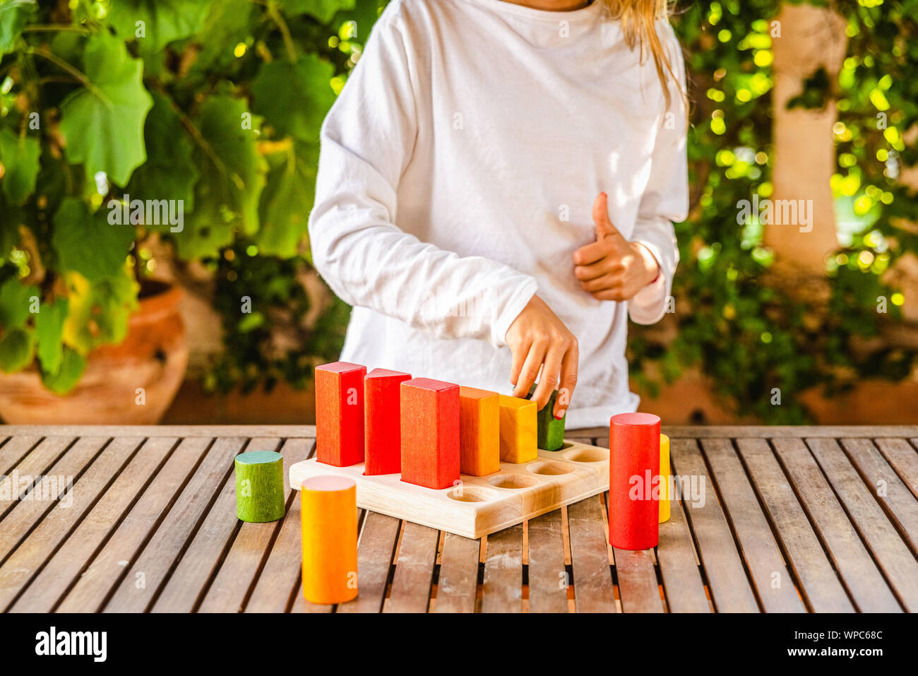 Ragazza posizionando i blocchi che una geometrica puzzle montessori di colori, un giocattolo realizzata con legno e sostenibile ed ecologico di colori. Foto Stock