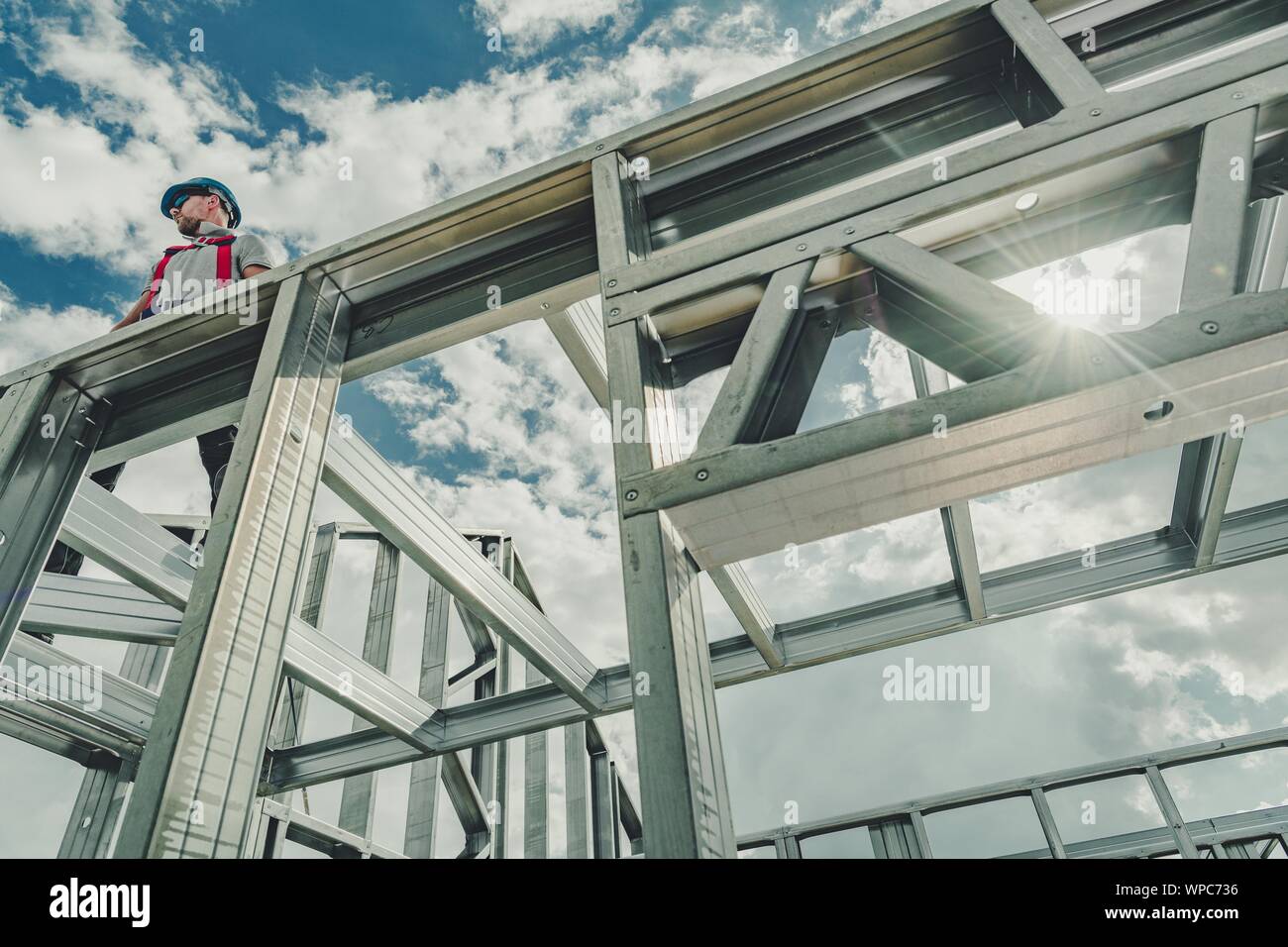 Lo scheletro di casa in acciaio costruzione del telaio. Imprenditore caucasico lavora in altezza. Cablaggio di sicurezza attrezzatura. Tema industriale. Foto Stock