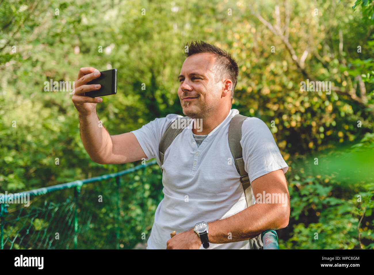 Escursionista prendendo foto nel verde della foresta con smart phone Foto Stock