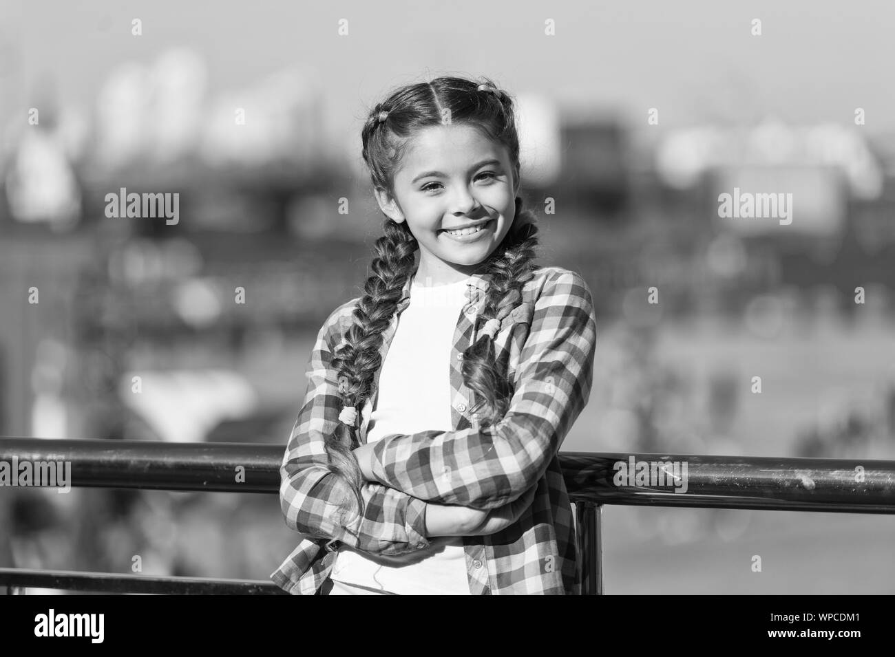 Le opzioni per il tempo libero. Tempo libero e svago. Ragazza carina kid con trecce rilassante background urbano sfocato. Organizzare attività per ragazzi. Una vacanza di piacere. Cosa fare per le vacanze. Giornata di sole a piedi. Foto Stock