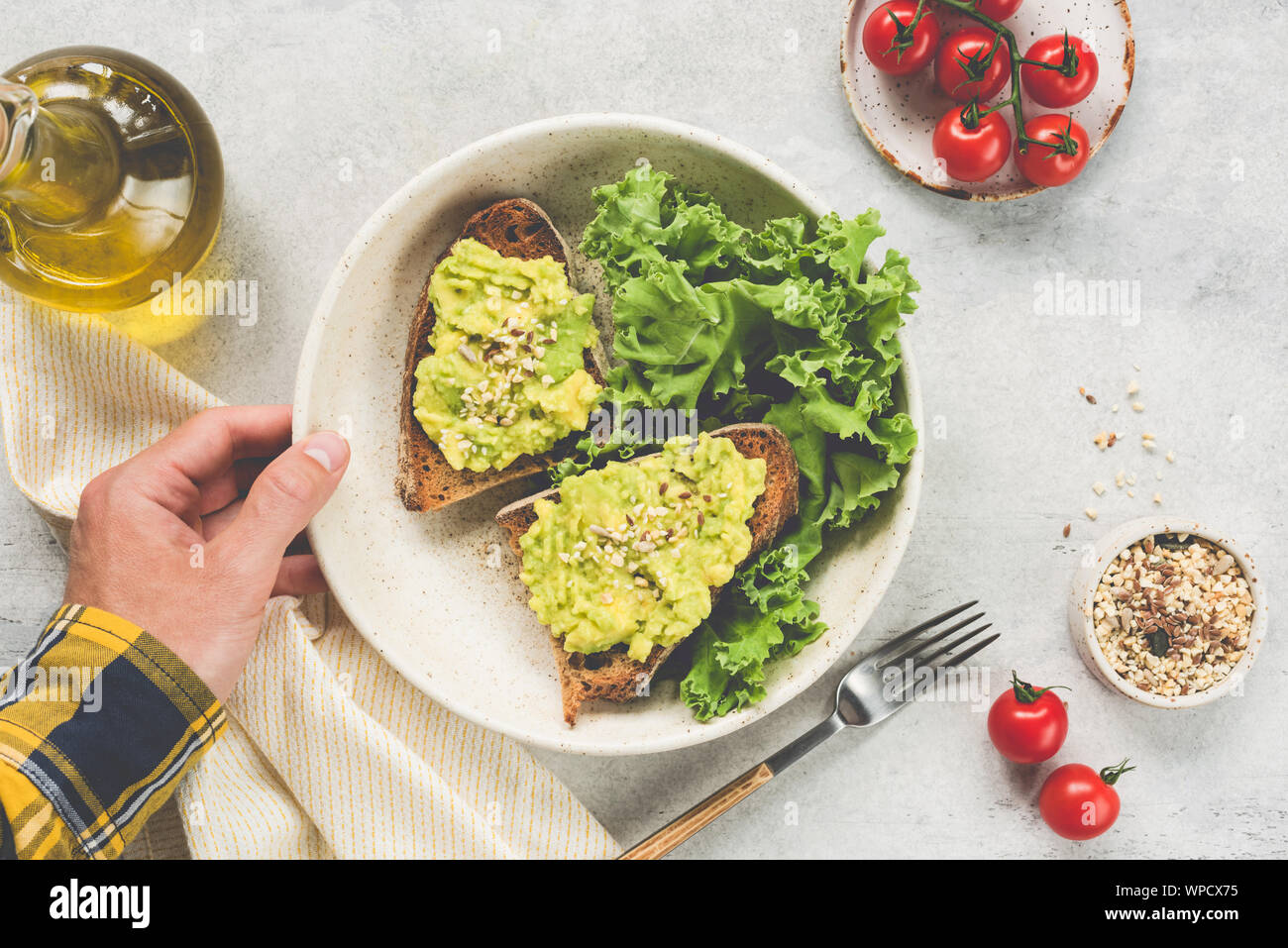 Toast con avocado, semi servito con insalata verde. Vista dall'alto. Maschio lato piastra di contenimento con vegan cibo vegetariano. Tabella vista dall'alto. Concetto di eati pulito Foto Stock