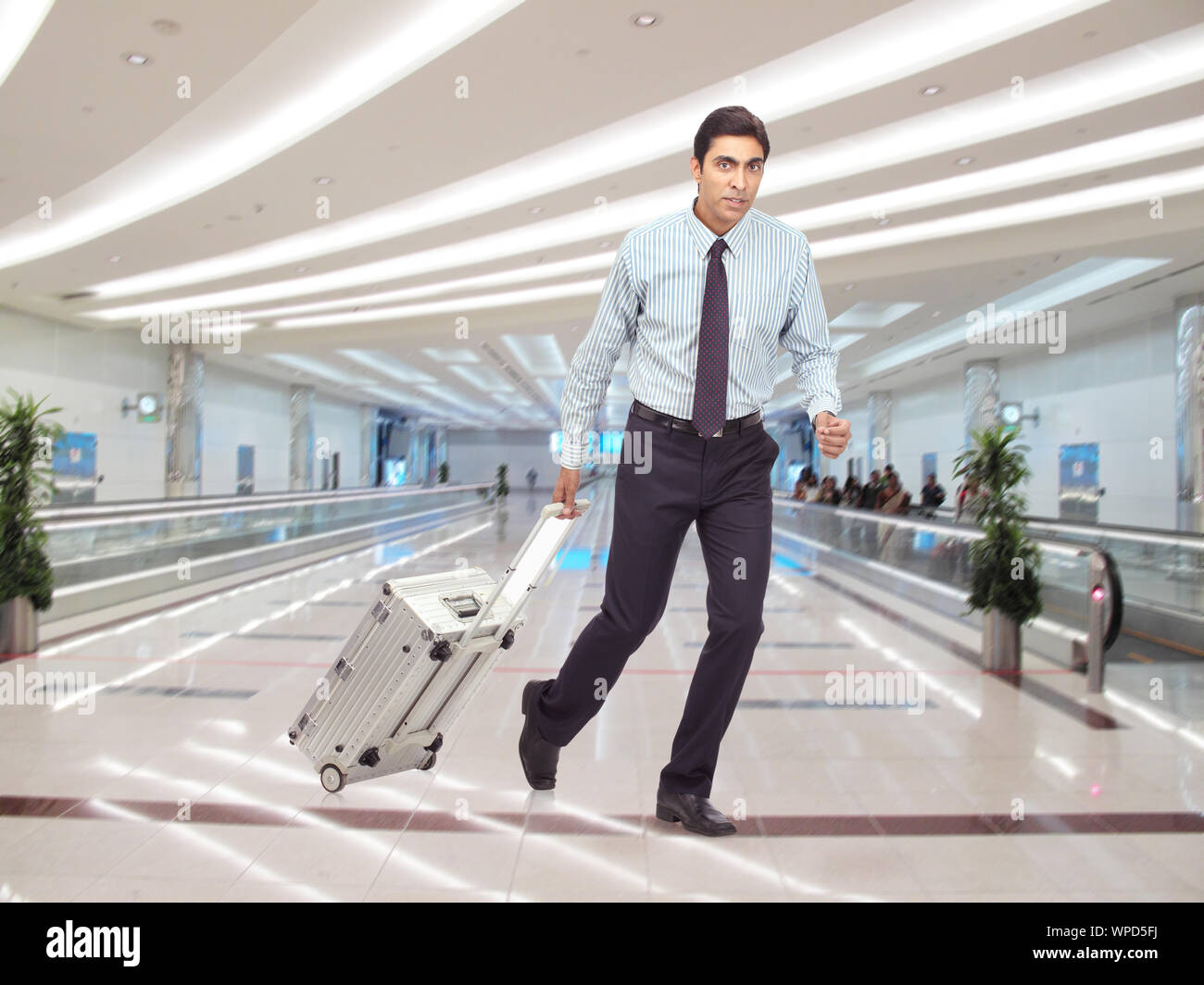 Un uomo d'affari in fretta con la valigia tirata all'aeroporto Foto Stock