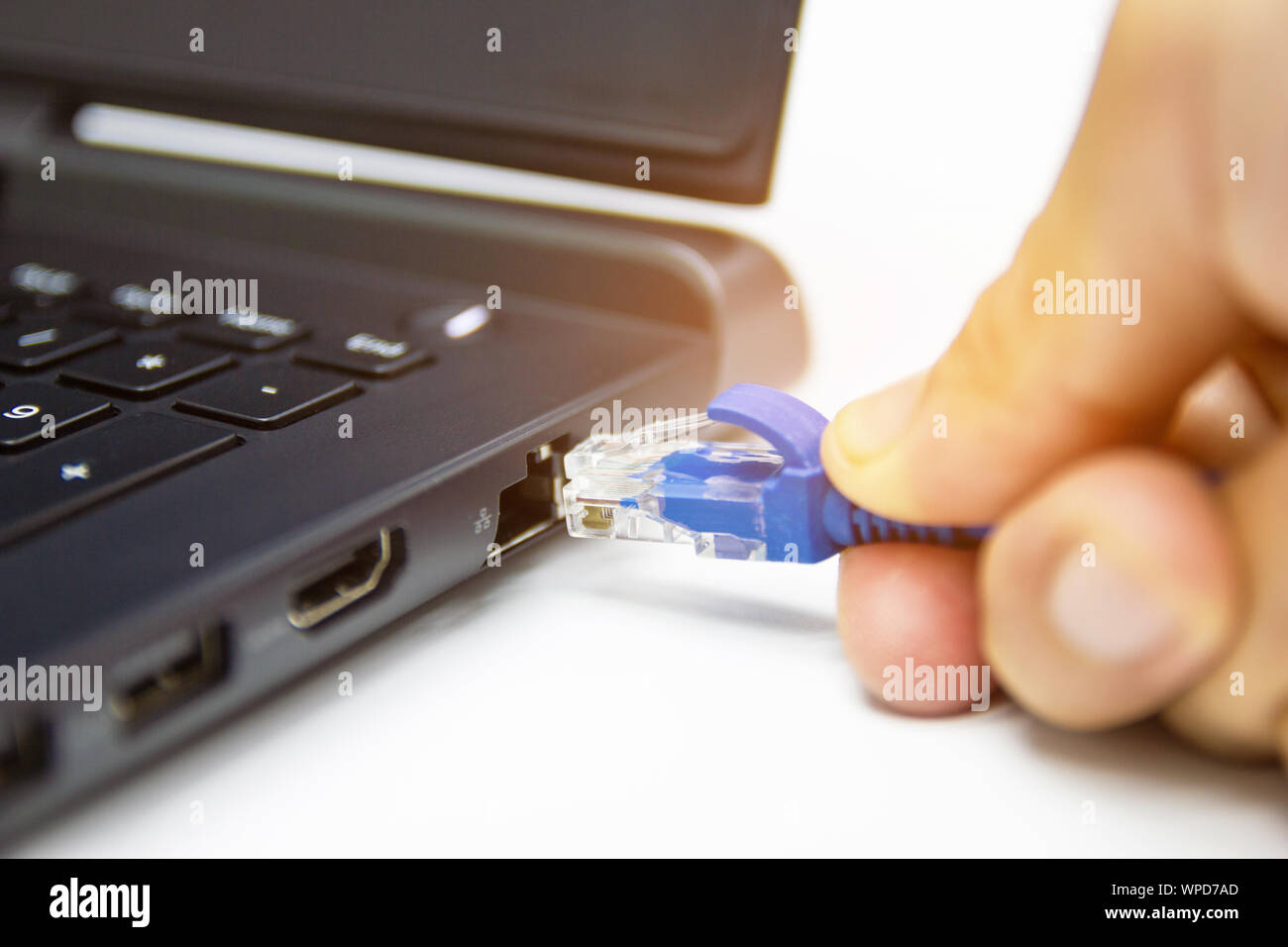 Primo piano il cavo blu connessione di rete a una porta LAN del computer portatile sul tavolo bianco, concetto di connessione del computer a Internet e networking. Foto Stock