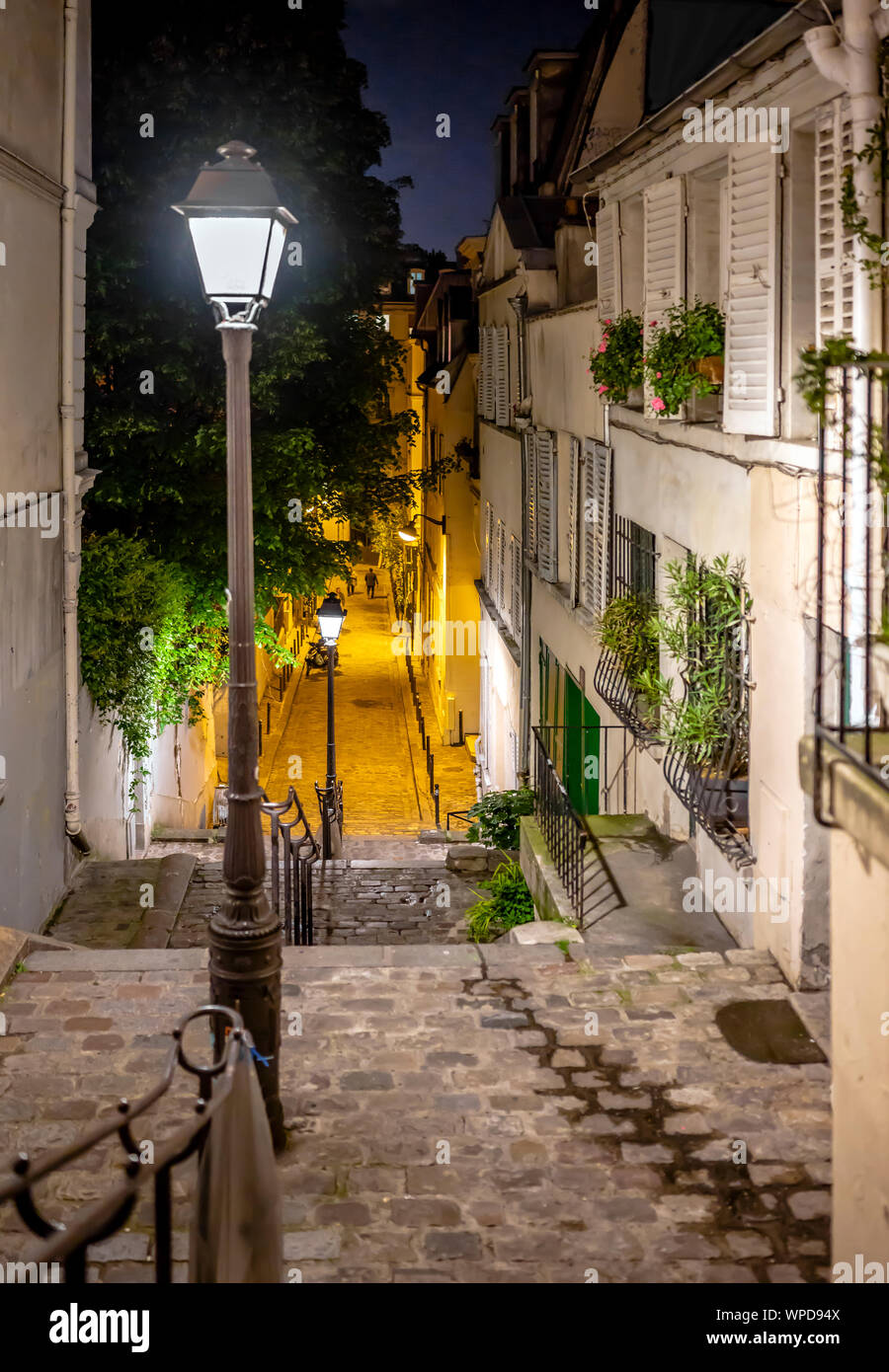 La notte vista dalla collina di Montmartre a Paris street giù per le scale con le luci di strada acceso in mezzo che attraggono folle di Foto Stock