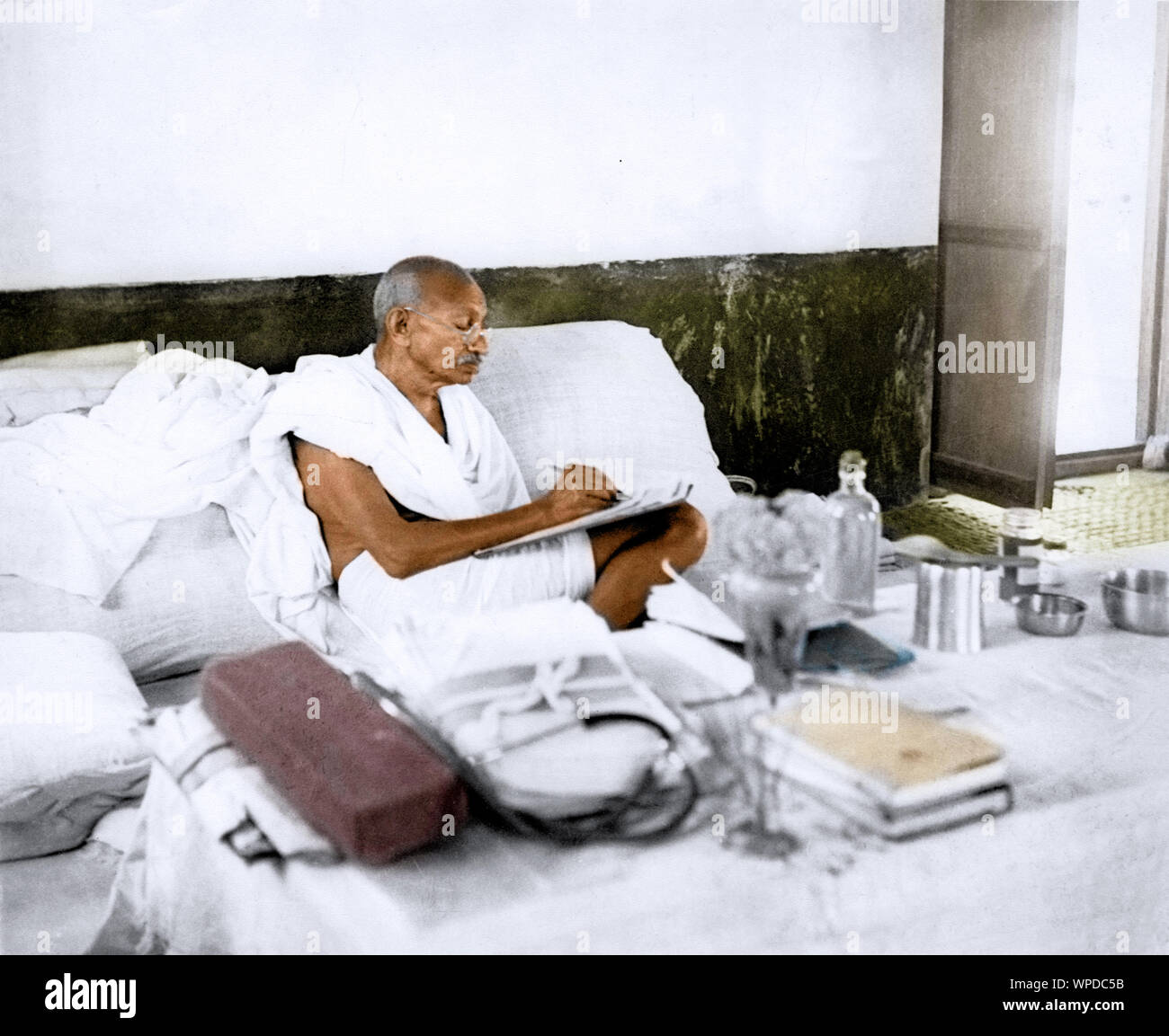 Il Mahatma Gandhi la scrittura seduto contro il piano di appoggio, India, Asia, 1939 Foto Stock