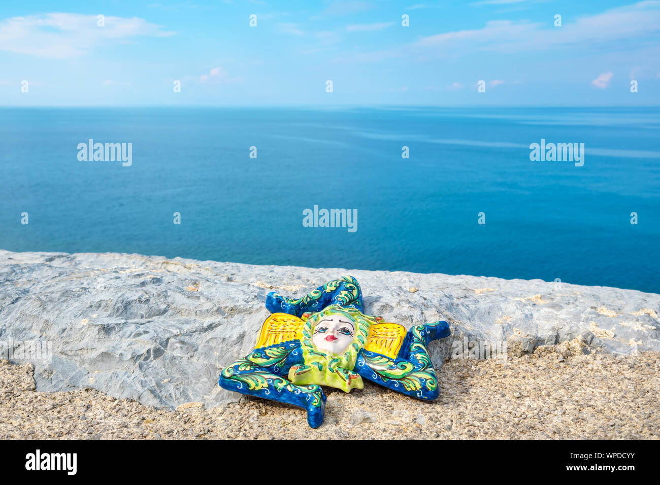 Tradizionale souvenir siciliano, Trinacria in ceramica su una pietra vicino al mare. Cefalu, Sicilia, Italia Foto Stock