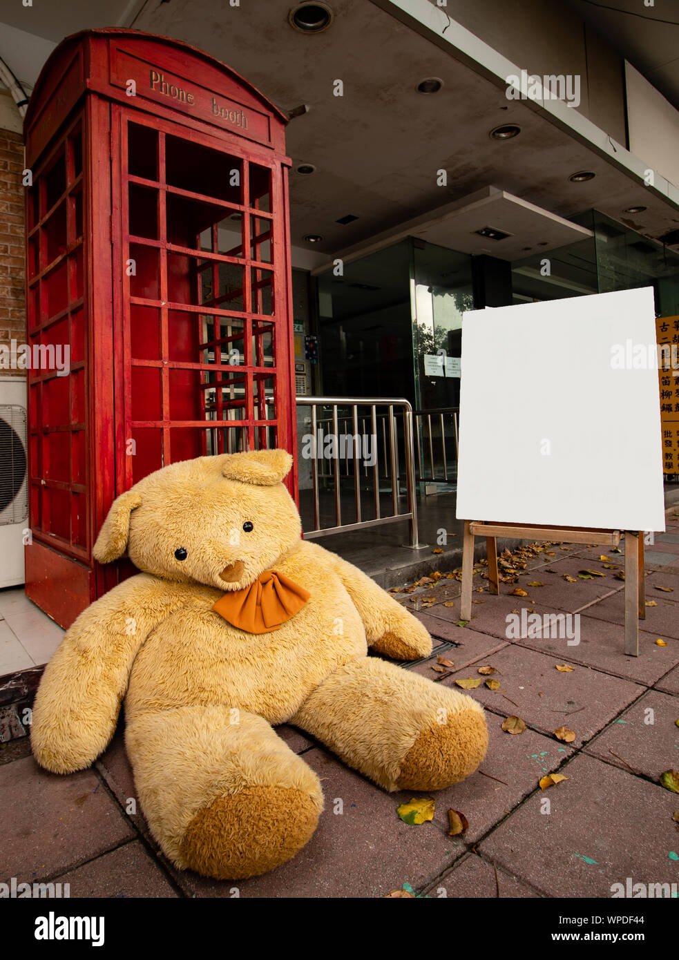 Un gigantesco orsacchiotto si siede accanto a un telefono rosso casella al di fuori di un negozio nuziale in Taipei Foto Stock