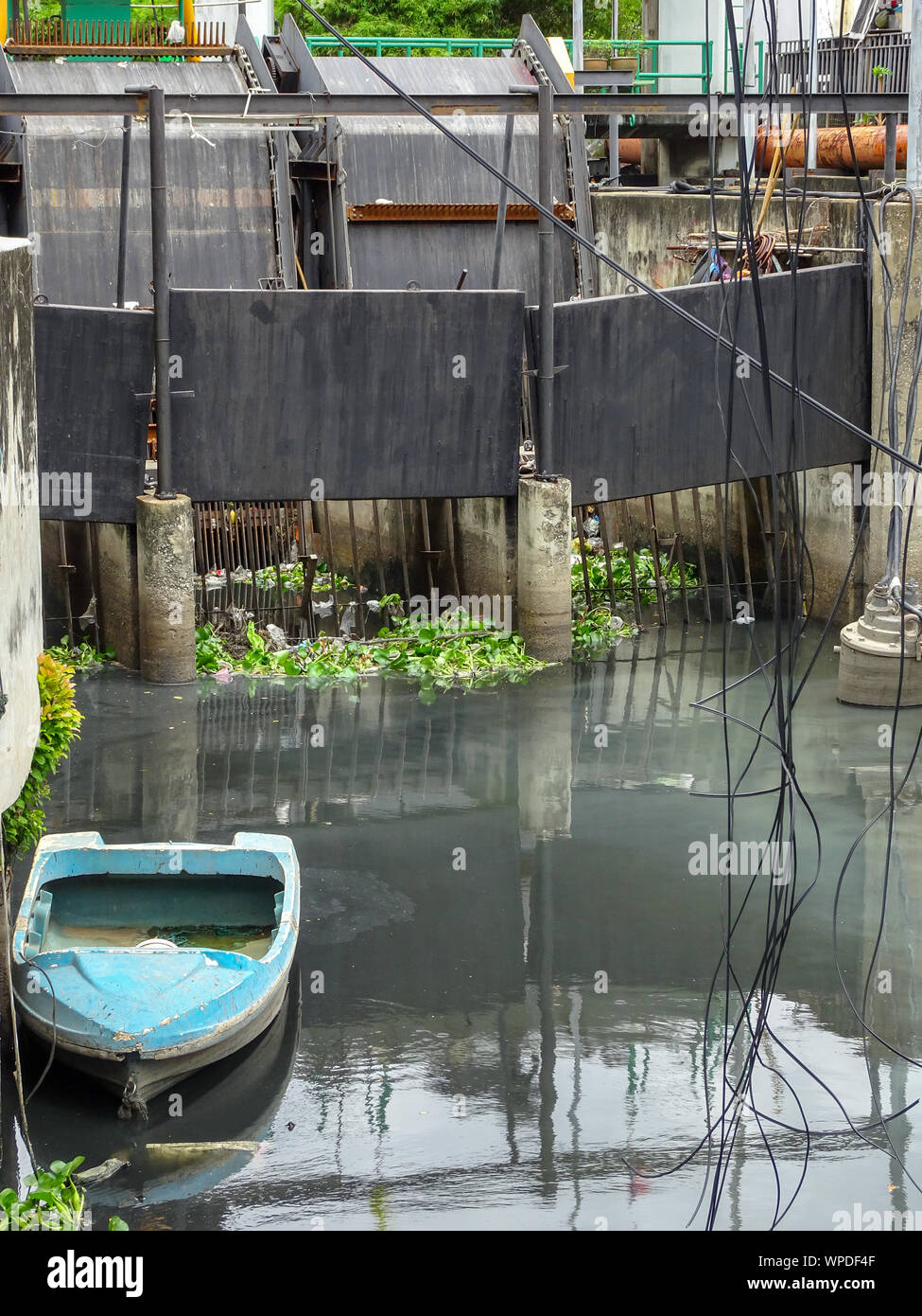 Una piccola barca galleggiante in acqua inquinata in Bangkok Foto Stock