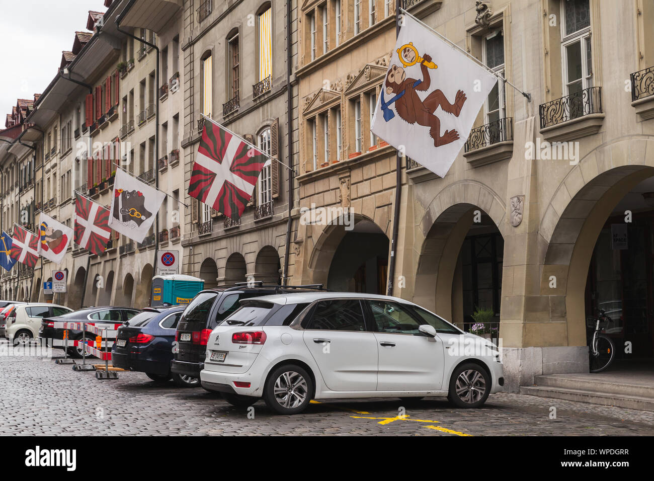 Bern, Svizzera - 7 Maggio 2017: Street View di Kramgasse o bottegai vicolo. Le macchine vengono parcheggiate sotto bandiere colorate dei cantoni svizzeri Foto Stock