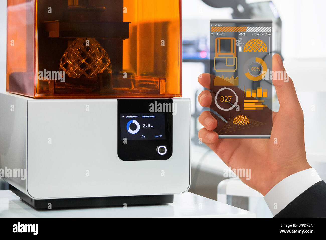 Mano con futuristico smartphone trasparente. Domanda di controllo stampante 3D in laboratorio. Foto Stock