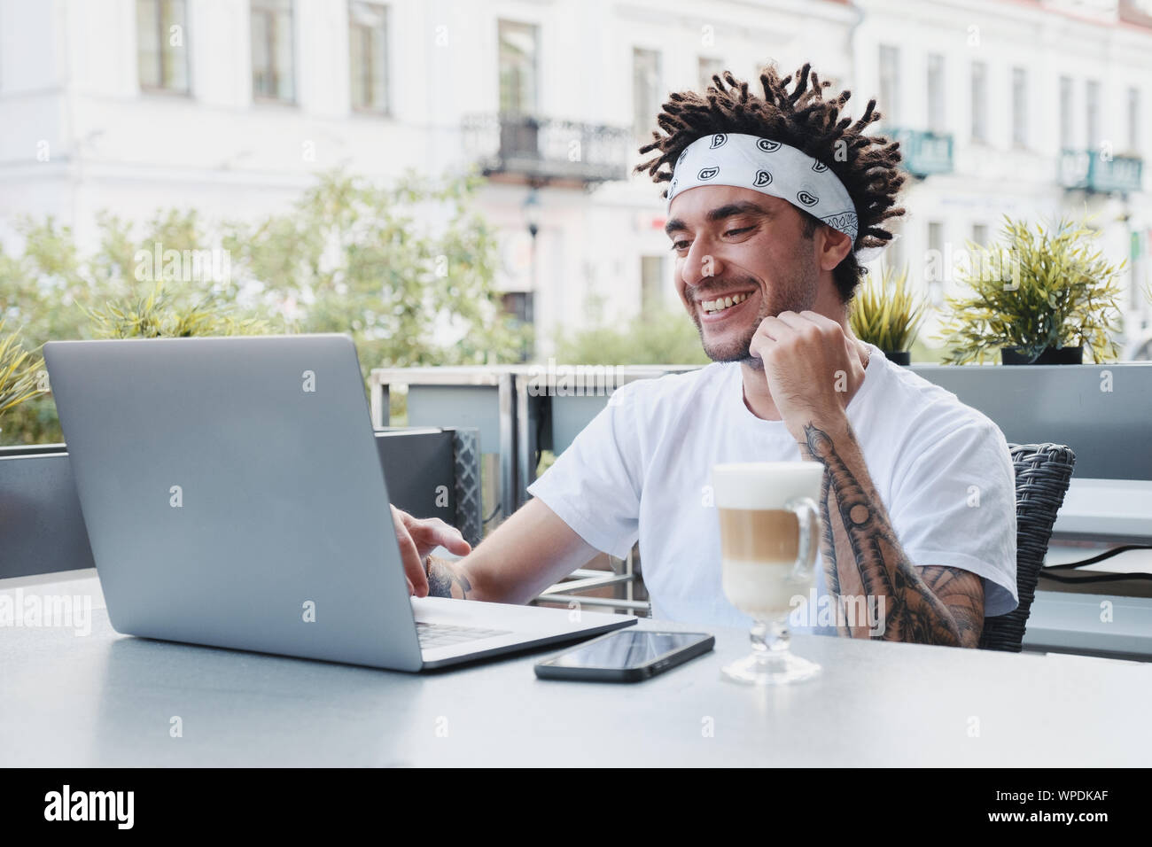 Tanga eccitato ragazzo con dreadlocks acconciatura gioire nel vincere una lotteria internet le scommesse effettuate sul sito web sul computer portatile. Bel uomo barbuto celebrando Foto Stock