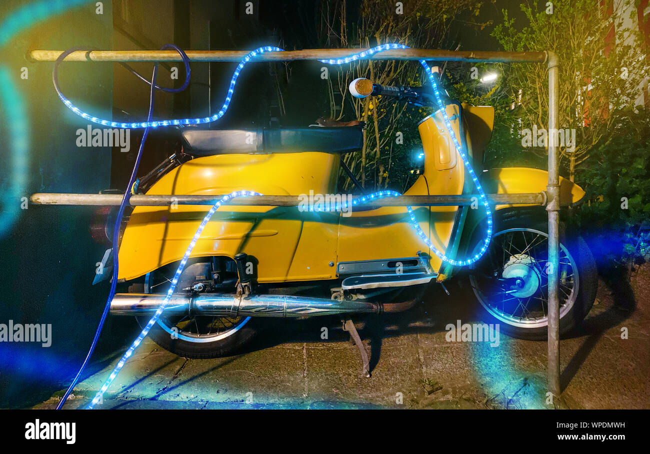 Giallo scooter blu con catena di luci. Foto Stock