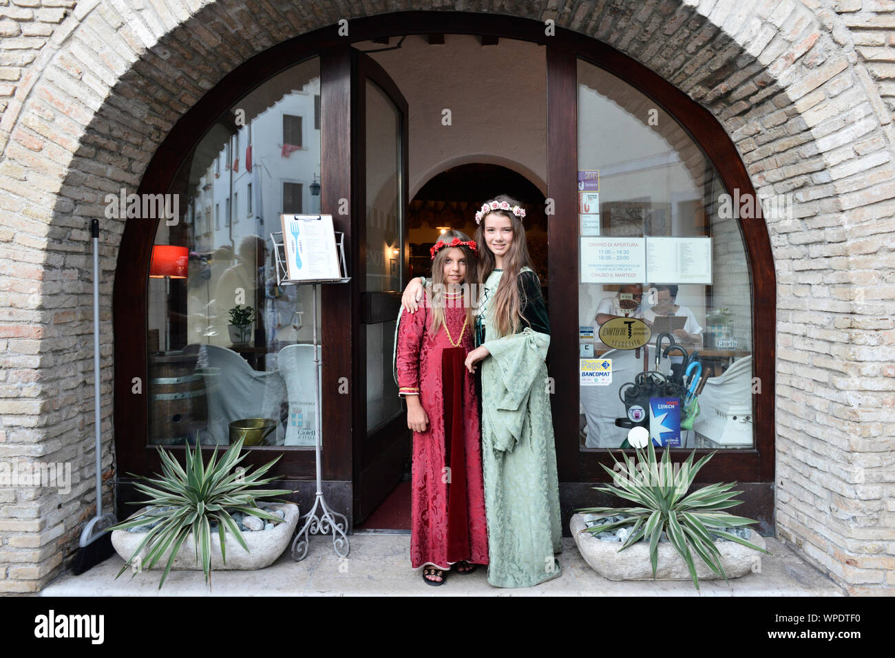 Vestito a festa le ragazze in abiti medievali durante l'annuale festival storici La Macia di fronte all'Enoteca La Torre. Spilimbergo, Italia Foto Stock