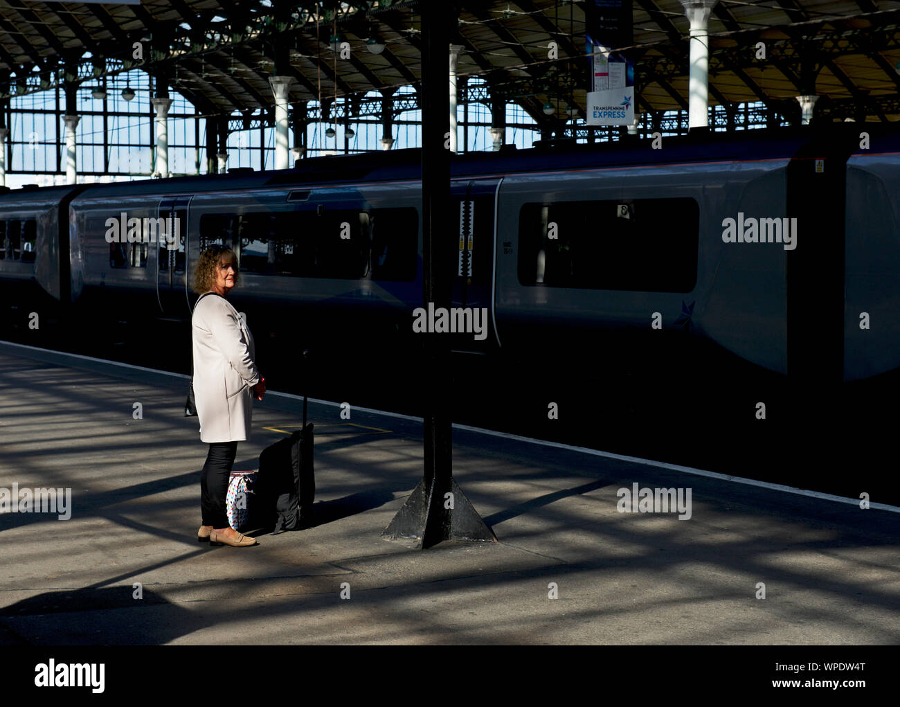 Donna di mezza età in attesa di un treno in Hull stazione ferroviaria, East Yorkshire, Inghilterra, Regno Unito Foto Stock